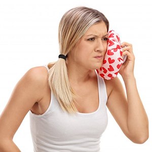 woman holding a cold compress to her cheek 