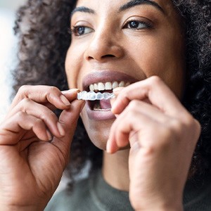 A woman putting on an Invisalign aligner