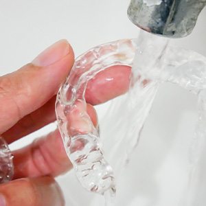 A man rinsing his Invisalign aligners