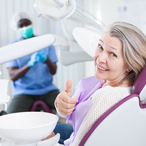 a mature dental patient giving a thumbs up