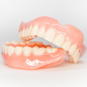 Full set of dentures in a glass of clear liquid on a tiled counter