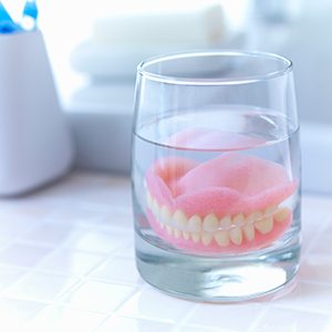 Older man smiling at reflection holding silver toothbrush
