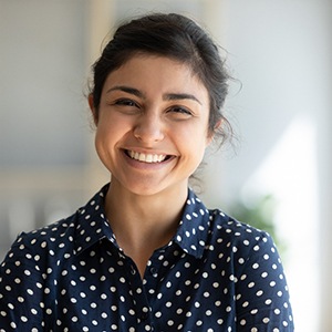 Woman with dotted shirt smiling at home