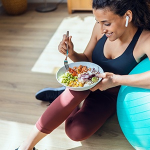 Woman leaning on exercise ball and eating a healthy meal