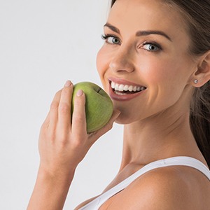 woman biting into a green apple