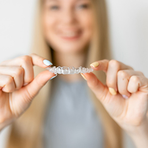 Closeup of woman holding Invisalign in Costa Mesa