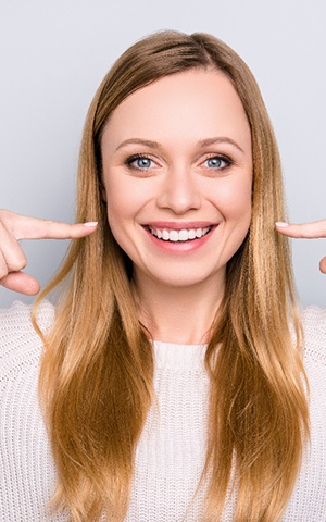 Woman pointing to her teeth after a smile makeover.