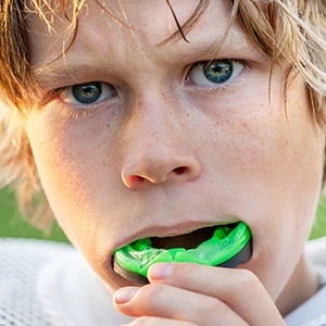 boy putting in green mouthguard