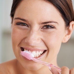 girl brushing teeth with pink toothbrush