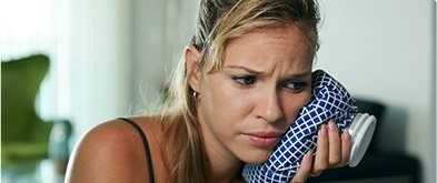 woman holding icepack on cheek