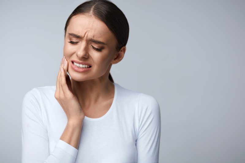 person with a toothache holding their cheek