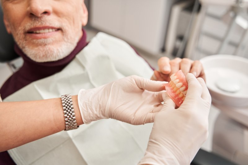 A dentist showing dentures to her patient