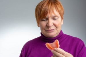 Woman with sores looking at her dentures