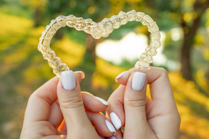 Hands holding clear aligners in a heart shape