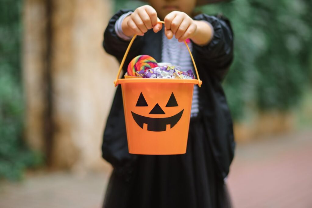 A child holding a bucket of Halloween treats
