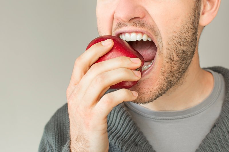 man biting hard apple in Costa Mesa