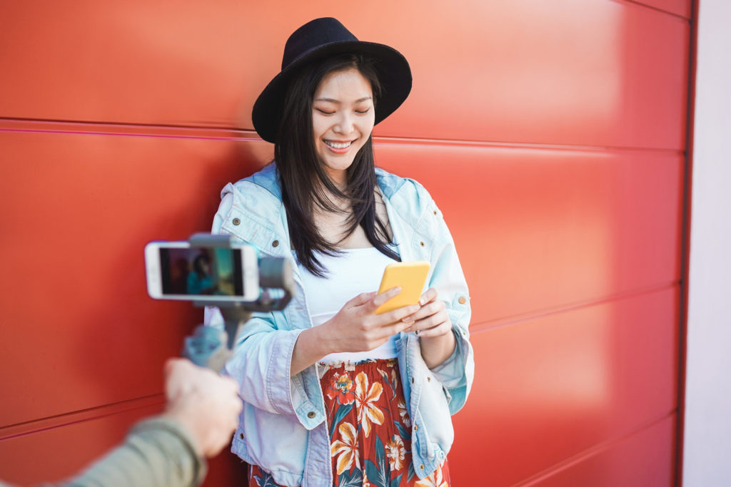 woman smiling while being recorded with cell phone camera